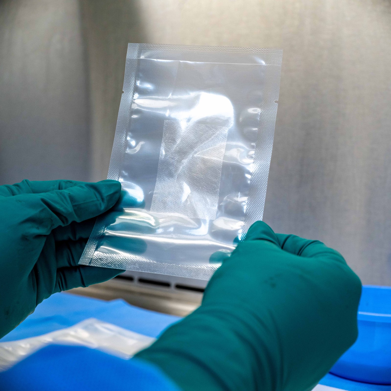 Gloved hands holding a clear pouch containing a membrane