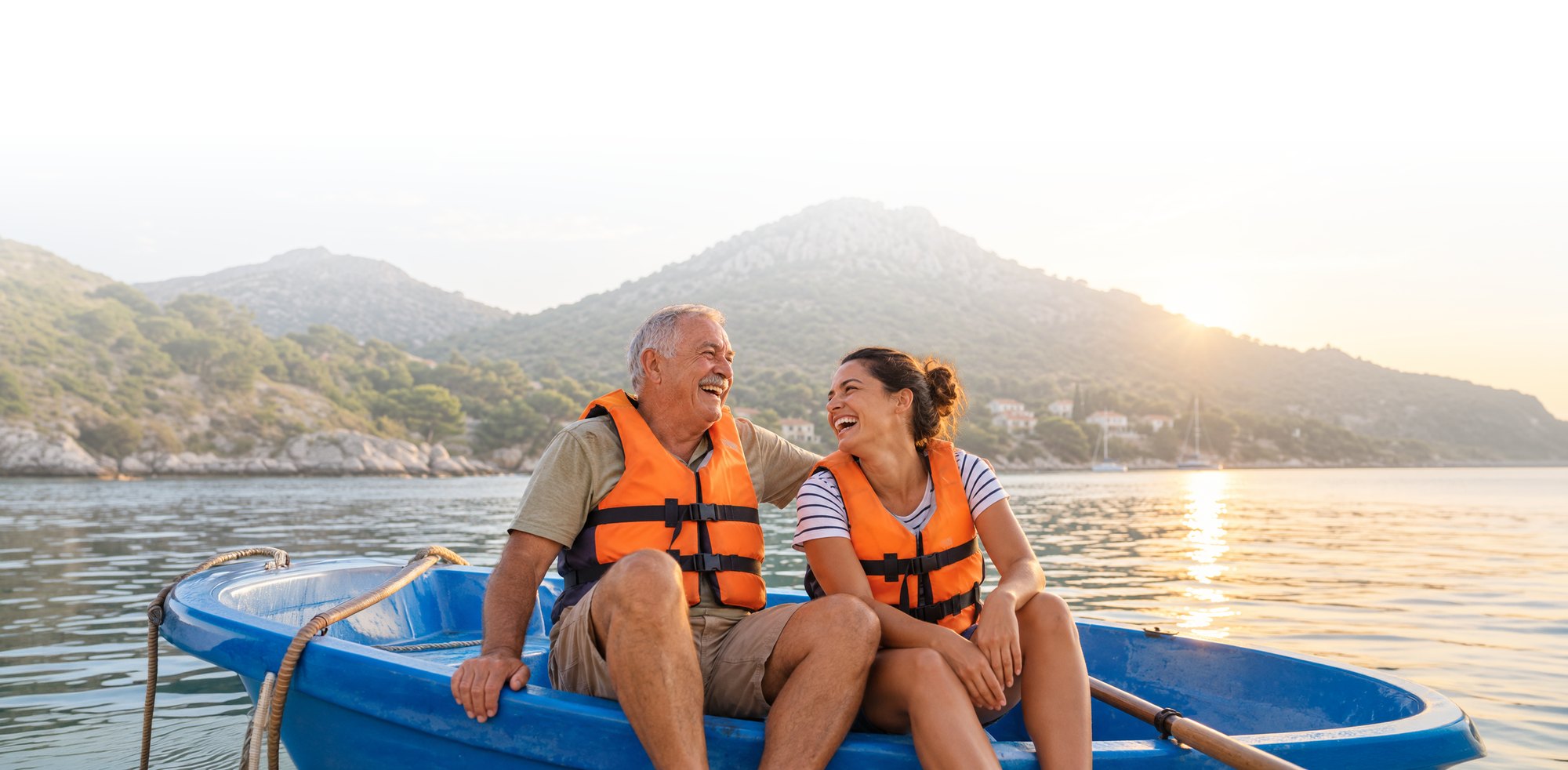 An older couple laughing together in a boat at sunset