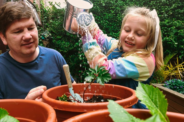 A man and a child watering plants in a garden