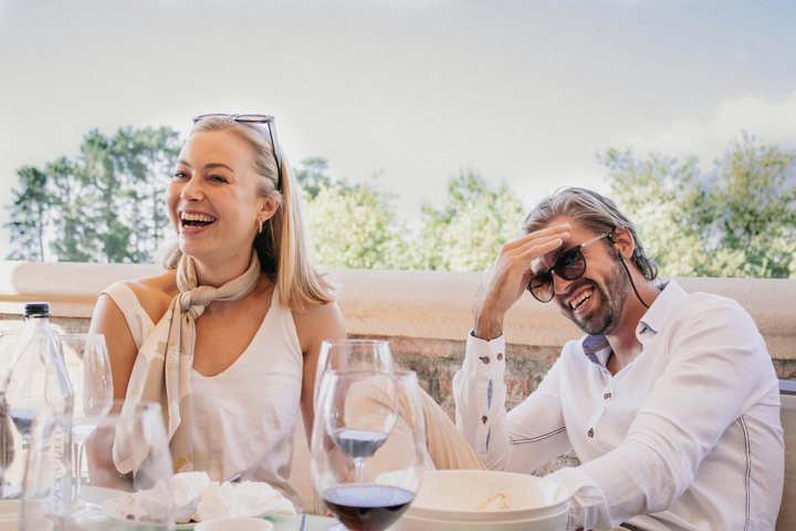 Two people laughing over a meal at a sunlit table